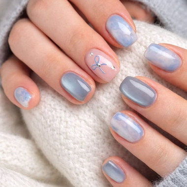Delikatny błękitny manicure z efektem kociego oka i kokardką